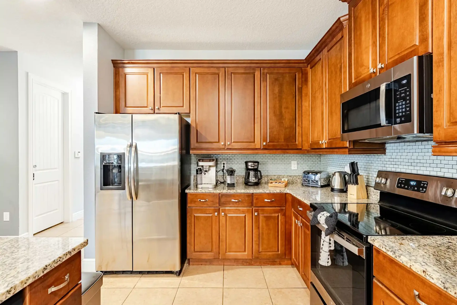 Kitchen with double door fridge, coffee machines and granite counters