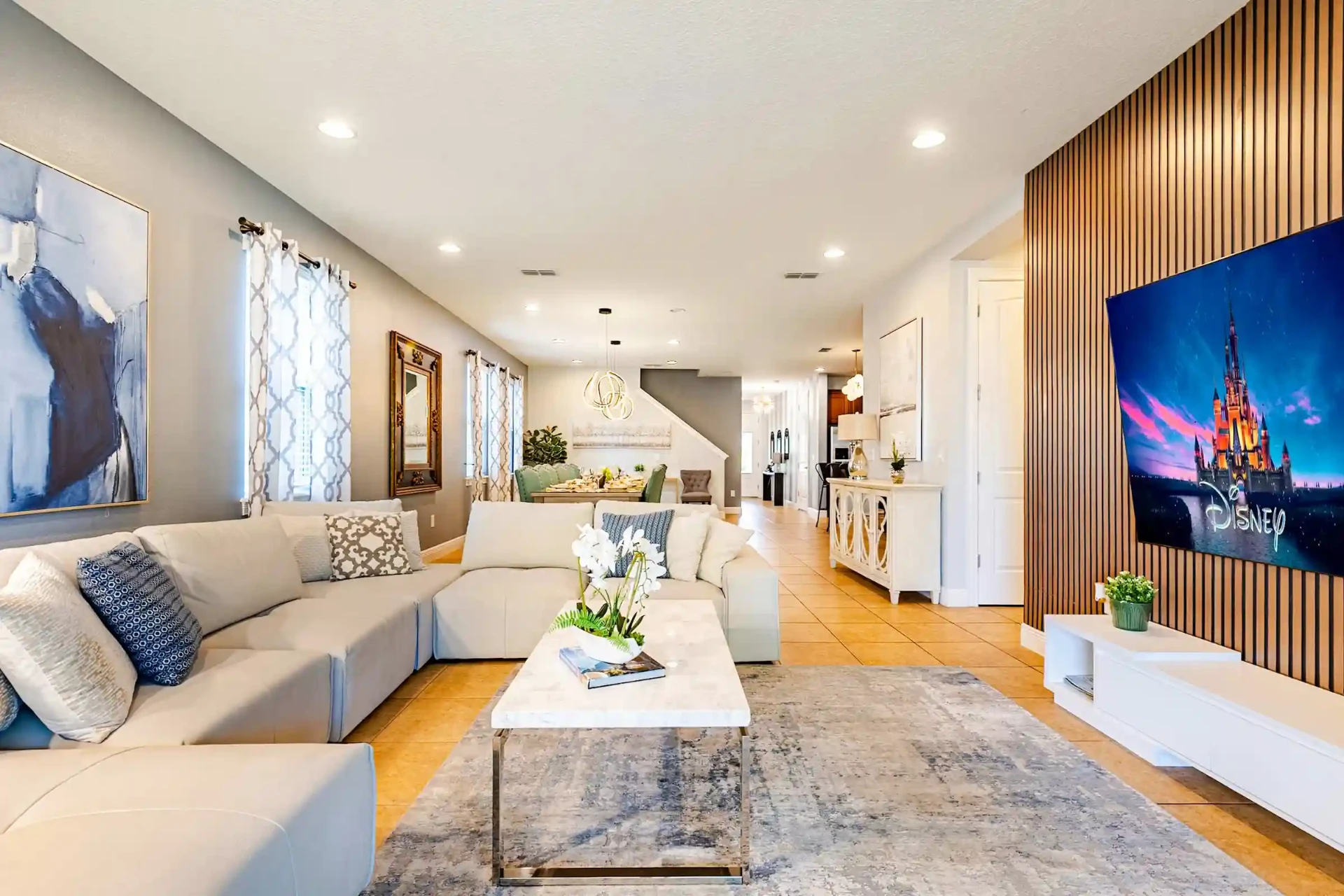 Open living room with large white sectional and Disney feature wall