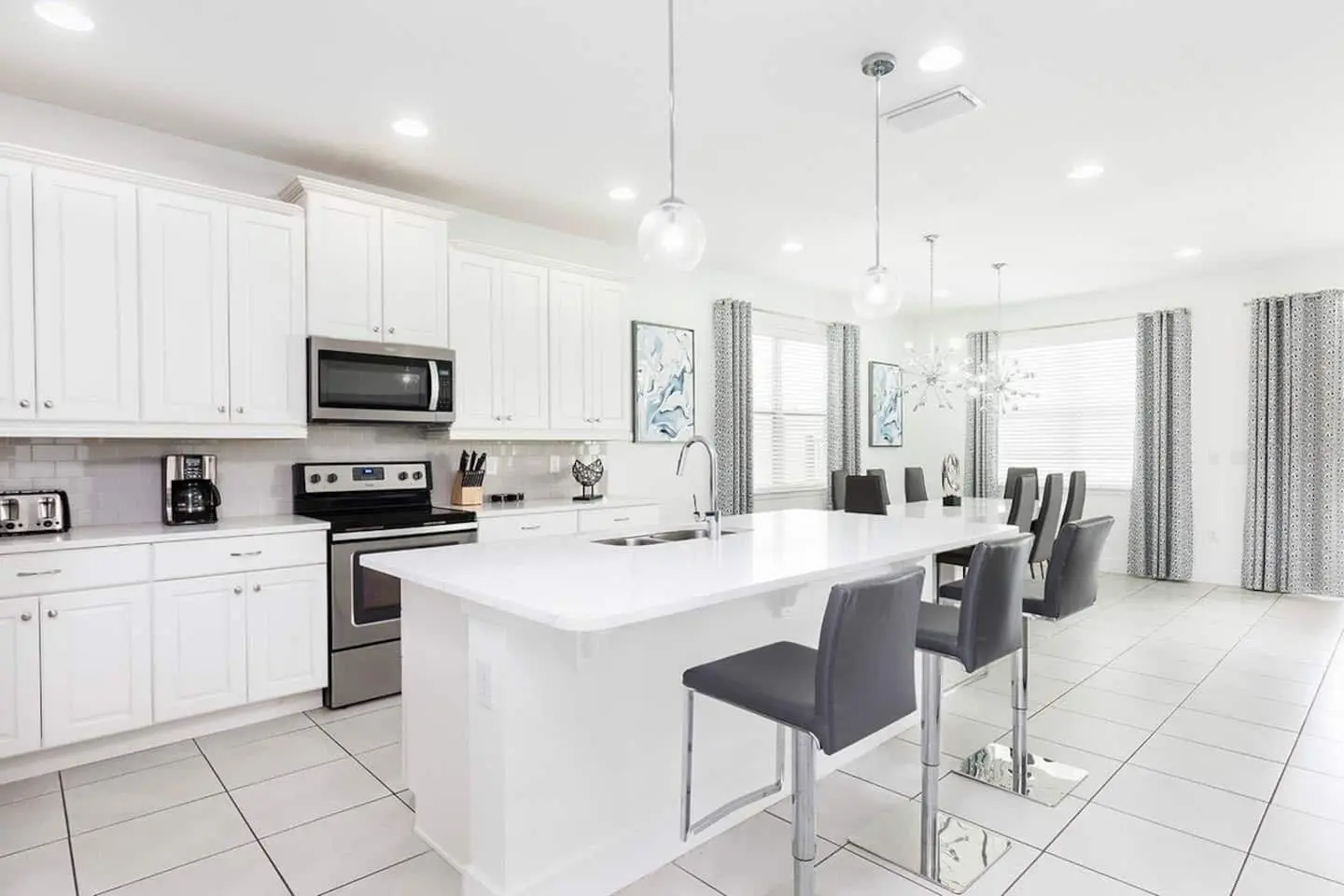 Bright white kitchen with quartz island, bar stools and dining beyond