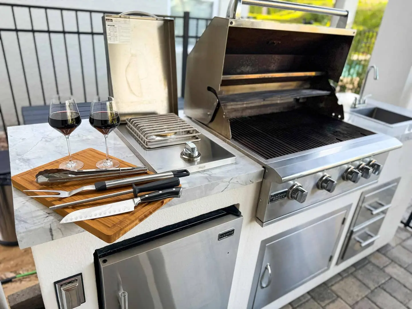 Built-in outdoor grill with marble counter, sink and wine glasses