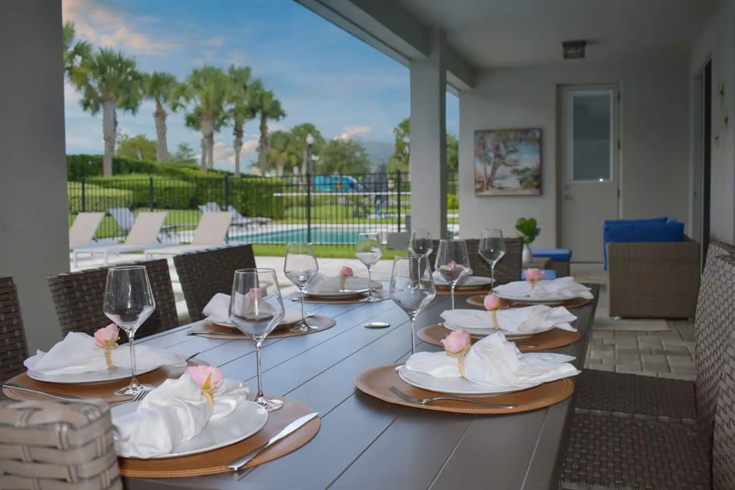 Covered outdoor dining table set with glassware overlooking the pool