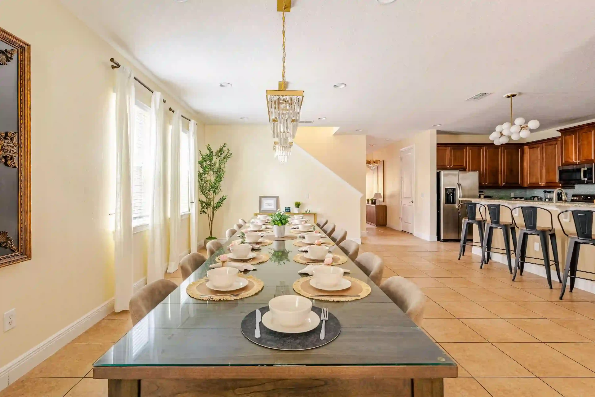 Long dining table set for twelve beneath modern chandeliers